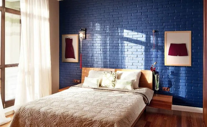 Двухспальная кровать в комнате с синей кирпичной стеной