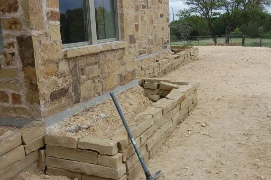 Вариант клумбы со стенками из камня, сделанной по периметру всего дома 