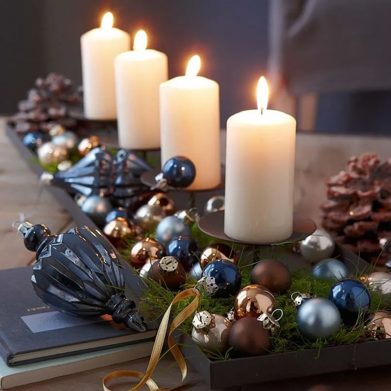Ароматические свечи, украшенные ёлочными игрушками послужат хорошим дополнением новогоднего стола