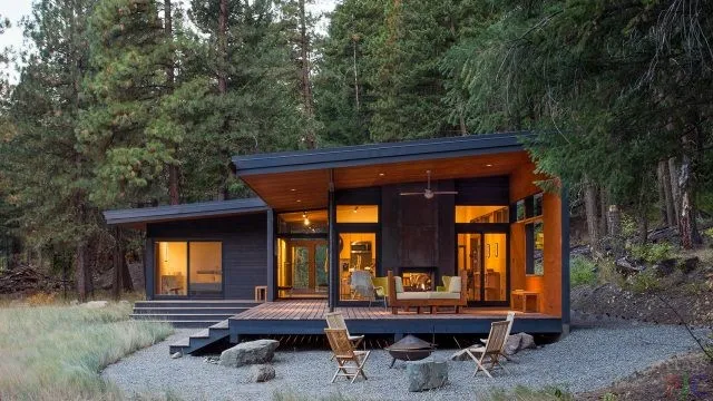 Освещённая веранда лесного дома с односкатной крышей